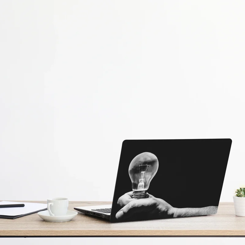 Naklejka na laptopa monochromatyczna ręka trzymająca żarówkę