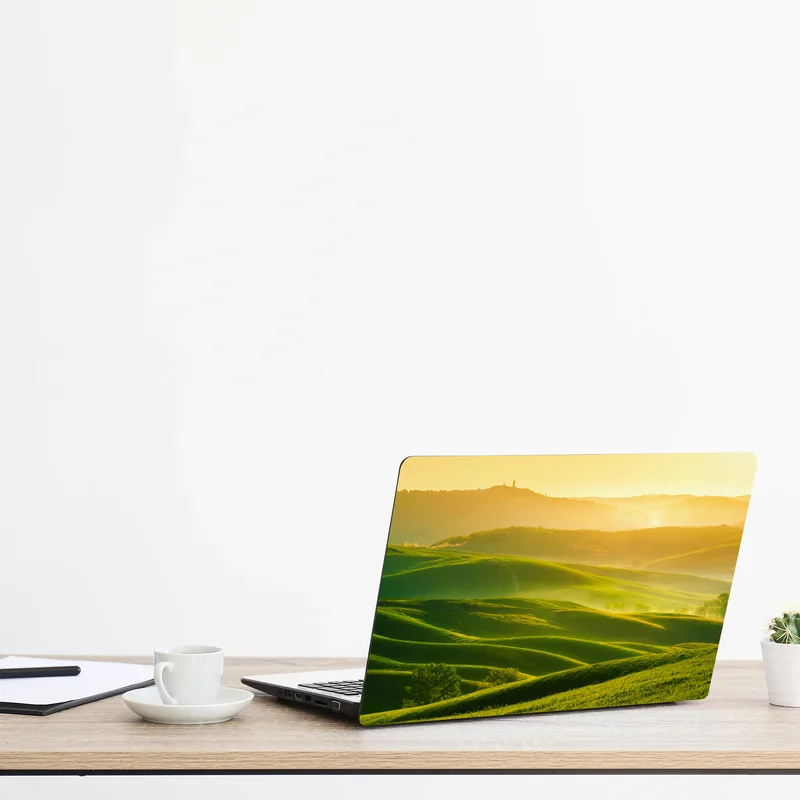 Laptop-Aufkleber goldener sonnenaufgang über sanften grünen hügeln