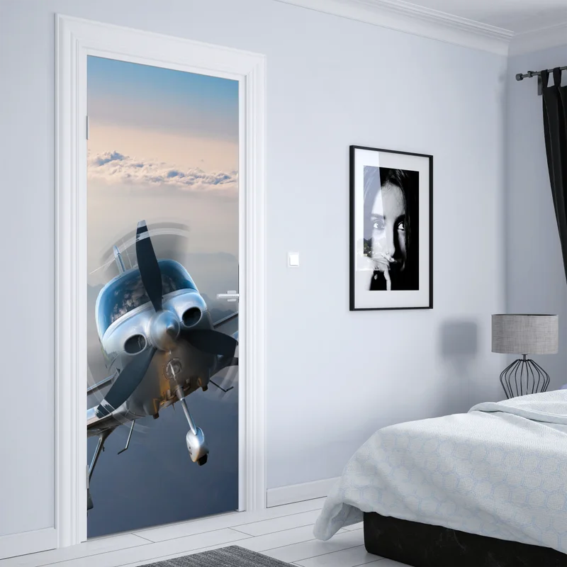 Türaufkleber silbernes propellerflugzeug über nebeligen bergen