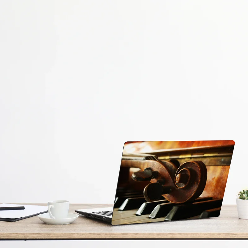 Naklejka na laptopa zabytkowa główka skrzypiec na klawiszach fortepianu Naklejka na laptopa zabytkowa główka skrzypiec na klawiszach fortepianu