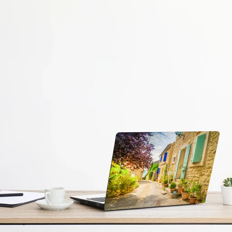 Laptop-Aufkleber sonnenbeschienene dorfstraße mit steinhäusern und bunten fensterläden